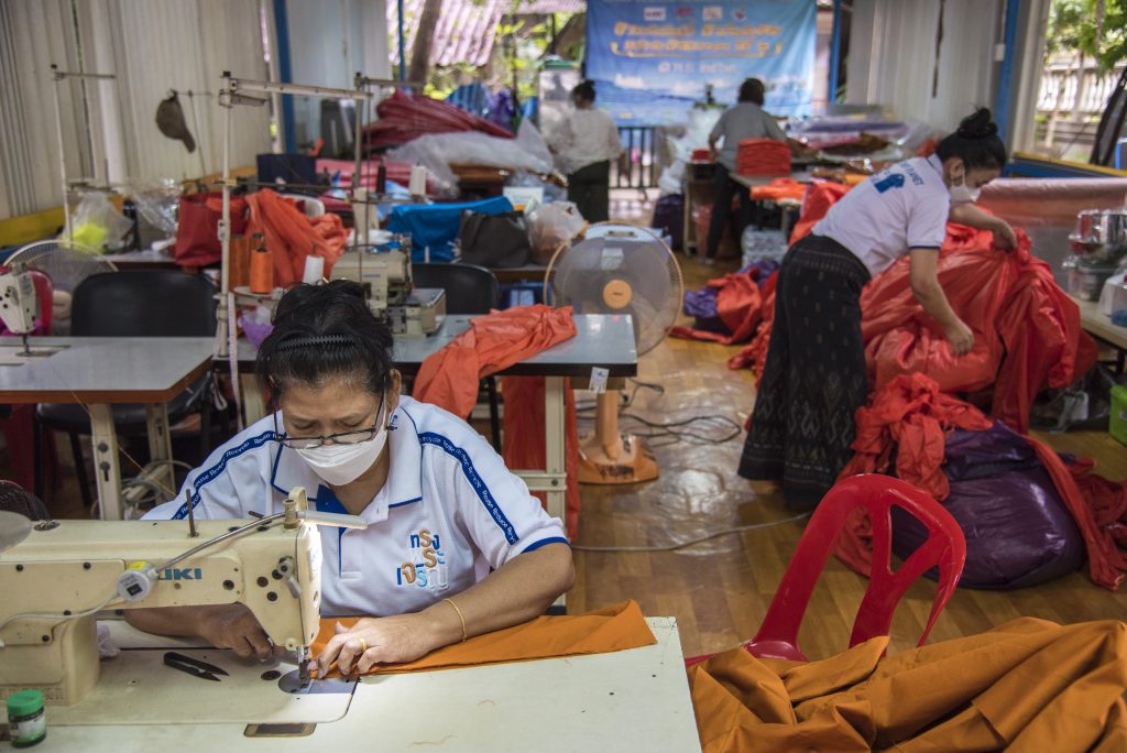 A woman sews a yellow robe in Bangkok. She works inside, but indoor workers also face economic loss due to heat.