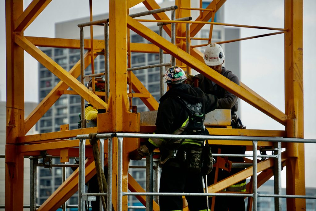 Image of construction workers on yellow steel scaffolding.