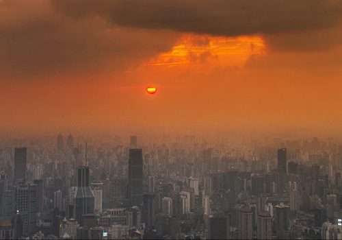 Heat haze over city skyline, where economic loss is often greatest due to heat. The sky is full of yellows and oranges and heavy clouds.