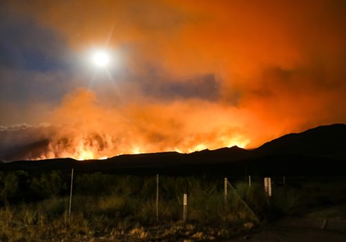 California wildfire with glowing orange smoke in the Sierra Nevada mountains.