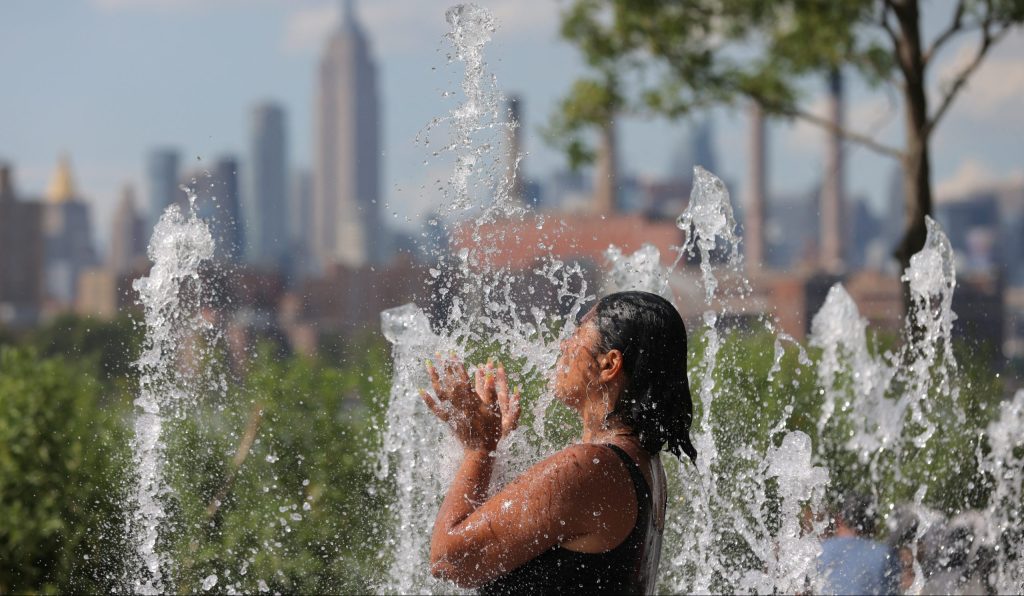 A person cools off in a water feature in Domino Park as a heat wave hit the region in Brooklyn, New York City, U.S., August 8, 2022. REUTERS/Andrew Kelly