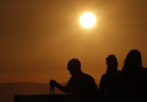 The sun shines on people standing on the roof observation deck of the Griffith Observatory, as a potentially dangerous heat wave grips the western U.S., in Los Angeles, California, June 29, 2013. Dozens of people were treated for heat-related ailments, and cities and towns across the western United States took emergency measures to help residents cool off, as the region sweltered on Saturday in dangerous triple-digit temperatures. REUTERS/Jonathan Alcorn (UNITED STATES - Tags: ENVIRONMENT SOCIETY)