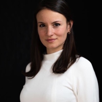 Portrait of Sabrina Nagel wearing a white shirt against a plain black background.