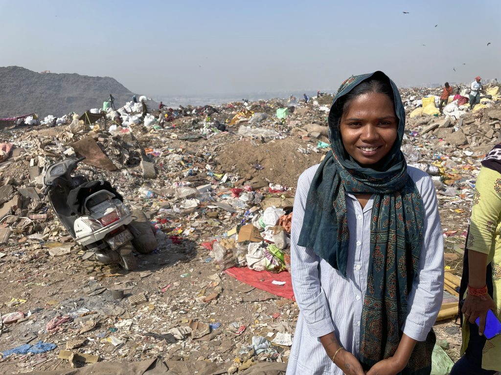 Alpa poses for a picture at her work site,  a sprawling landfill where she parses through waste for recyclable materials she may be able to sell. 