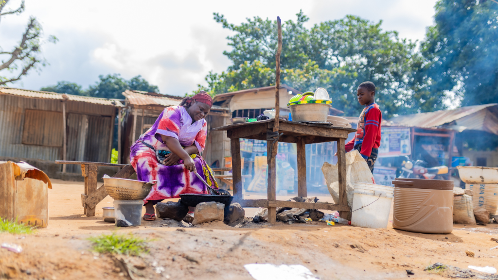 Image of woman cooking on outdoor fire in an open air market in Nigeria.