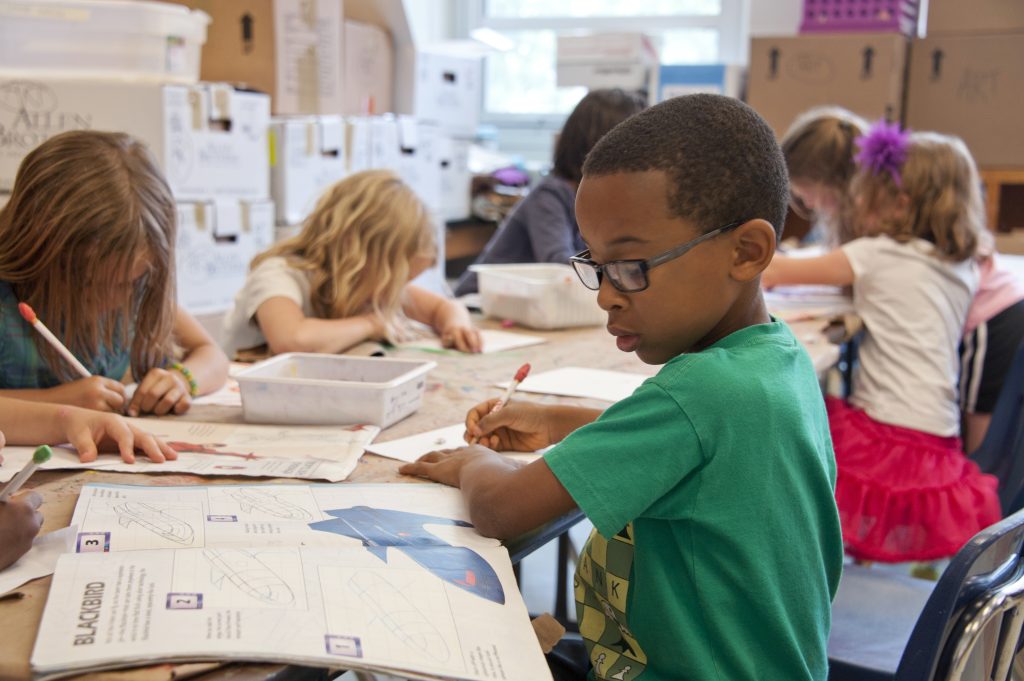 Captured in a metropolitan Atlanta, Georgia primary school, seated amongst his classmates, this photograph depicts a young African-American schoolboy who was in the process of drawing with a pencil on a piece of white paper. 