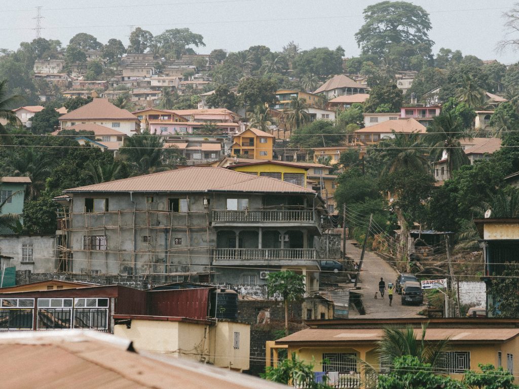 An aerial view of the Freetown skyline shows houses lined with trees for shade.