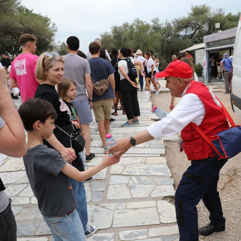 Red Cross volunteer distributes water to young boy.