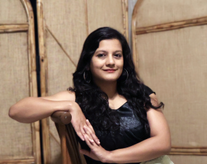 Apekshita Varshney sitting, looking to camera.