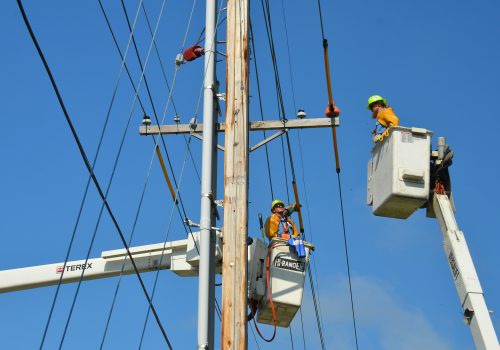 Two linemen on cherry pickers working on electric wires.